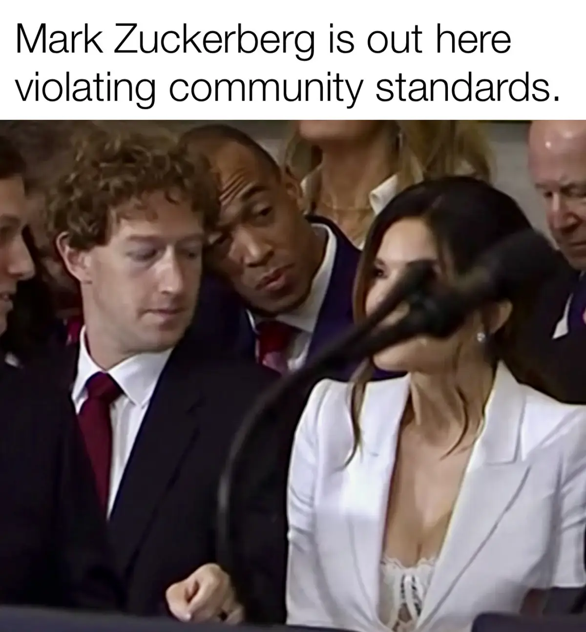 A still image from a formal hearing shows Mark Zuckerberg looking down with a serious expression, while a woman in a white…