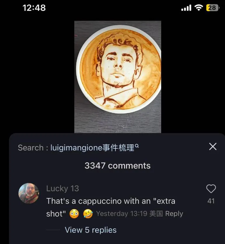 A close-up photo of a latte art cappuccino featuring a detailed portrait of a man with curly hair and a collared shirt…