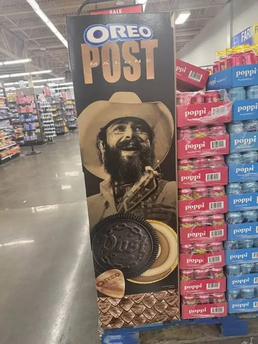 A tall, black promotional display for 'OREO MALONE' stands in a grocery store aisle, featuring a sepia-toned image of a…
