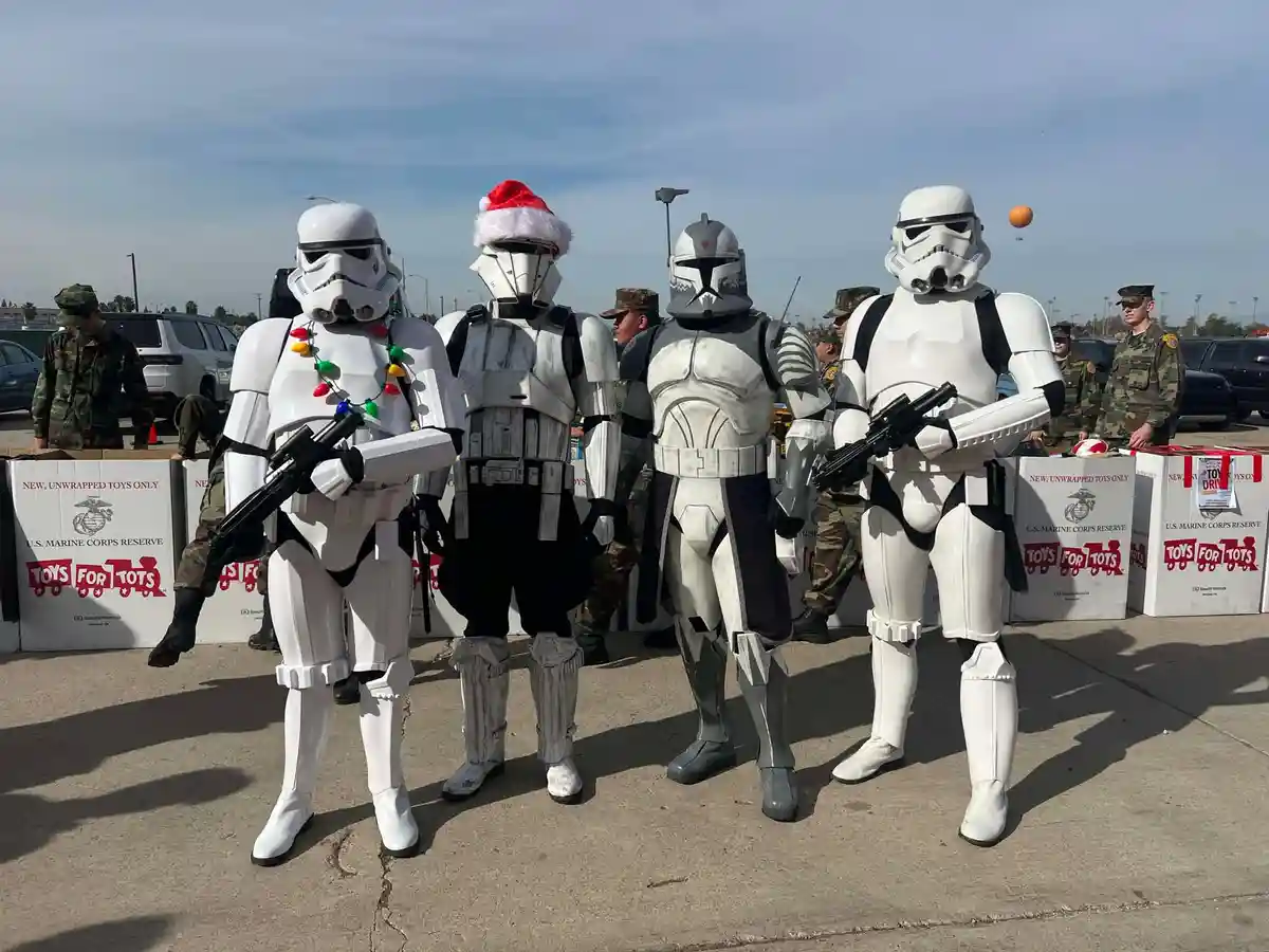 Four people in Star Wars costumes — two Stormtroopers, one Clone Trooper, and one with a Santa hat — stand in front of U.S…