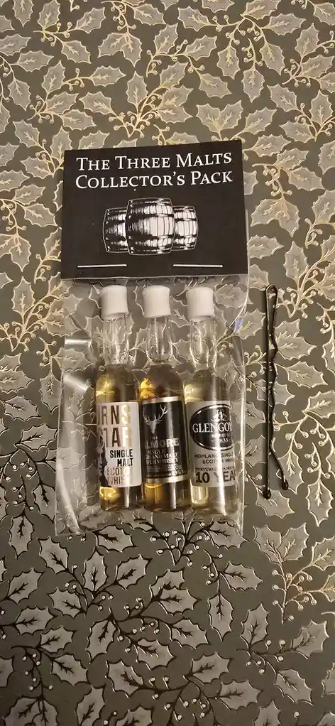 A clear plastic package containing three miniature bottles of single malt scotch whisky — labeled 'Burns Star', 'The Lmore'…