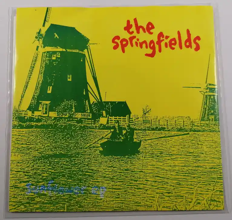 A vintage-style album cover featuring a stylized green and yellow illustration of windmills beside a body of water, with the…