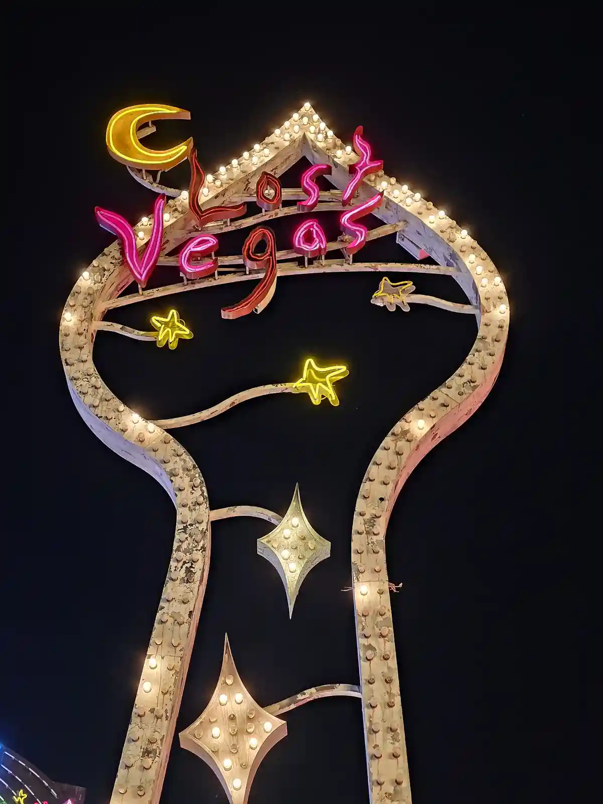 A nighttime photo of the iconic, weathered neon sign for 'Lost Vegas' shaped like a large key, adorned with glowing stars…