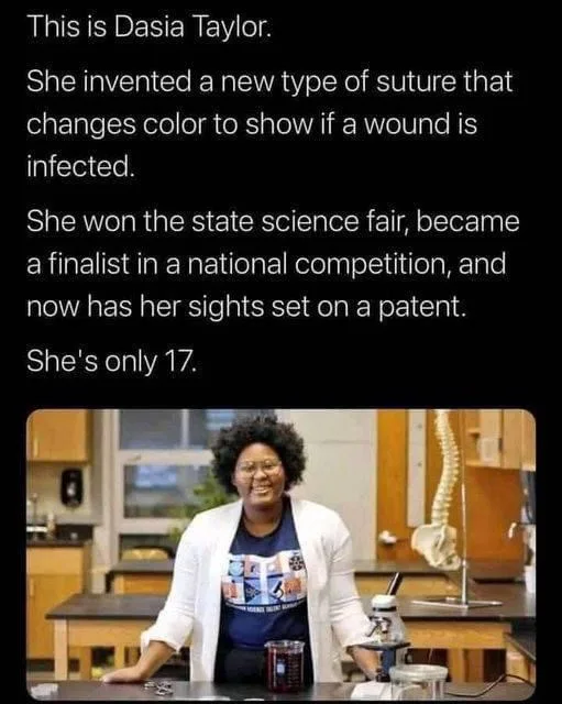 A young Black woman with curly hair and glasses, wearing a white lab coat over a graphic t-shirt, stands confidently in a…