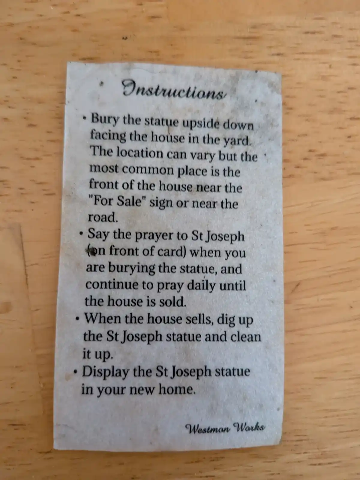 A close-up photo of a small, slightly worn paper card with printed text titled 'Instructions' resting on a wooden surface…