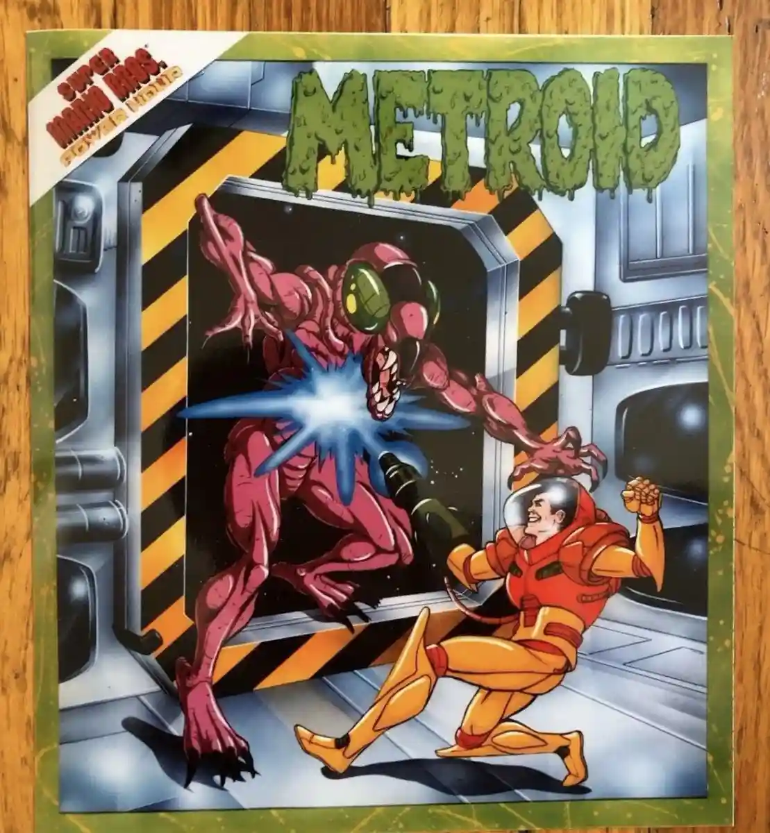 The image shows the cover art for the video game 'Metroid,' featuring a pink, alien creature with green eyes lunging at a…