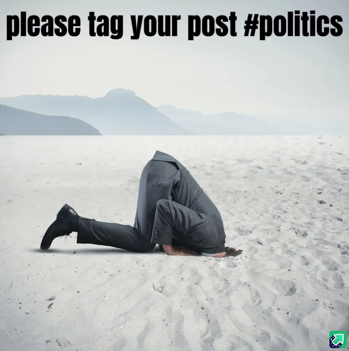 A person in a gray business suit is kneeling on a vast, sandy beach with mountains in the distance, burying their head in…