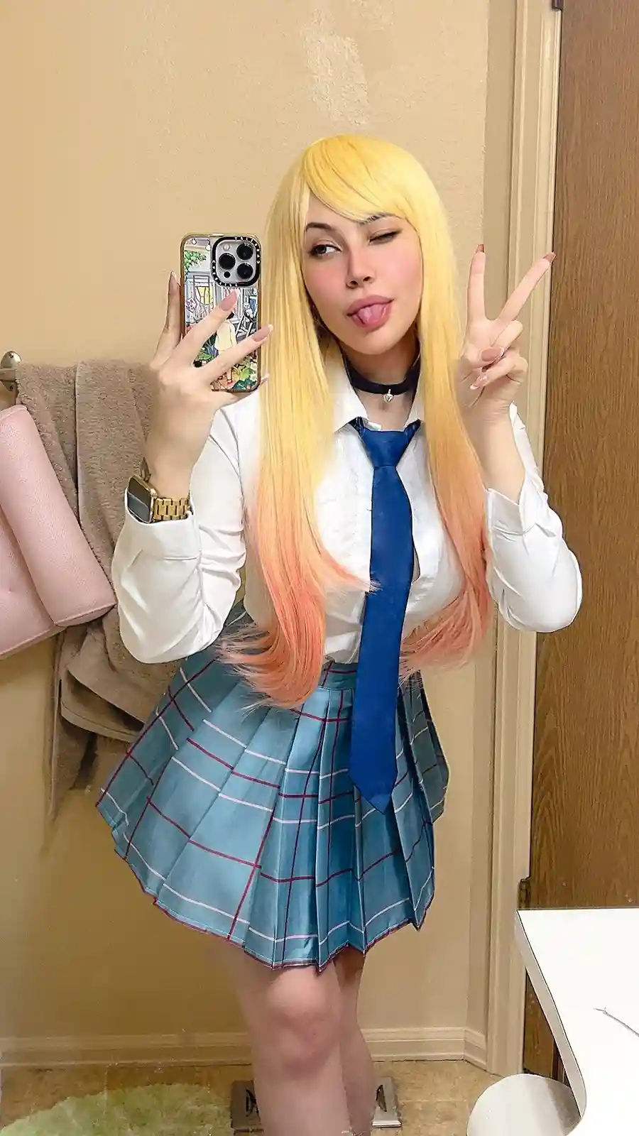 A person with long blonde hair that fades to peach at the ends poses in a mirror selfie wearing a white collared shirt, blue…