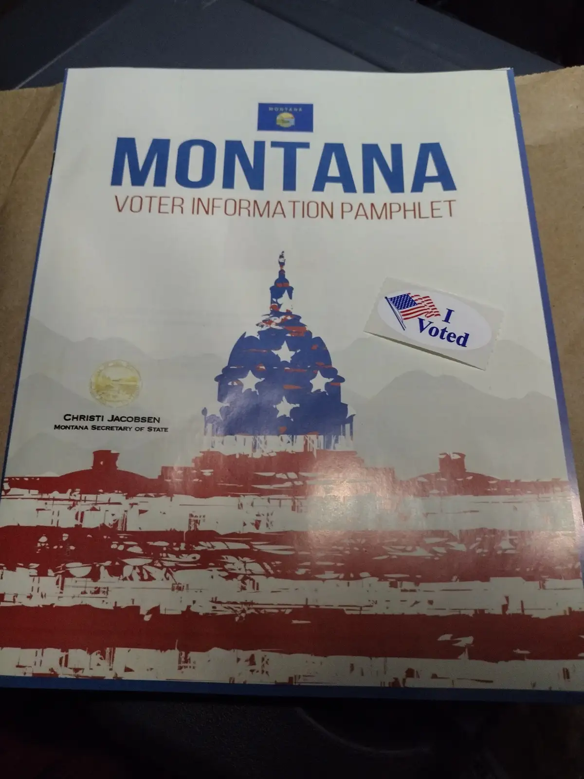 A Montana Voter Information Pamphlet featuring the state capitol building in red, white, and blue, with an 'I Voted' sticker…