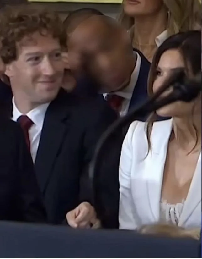 A still image from a public event shows Mark Zuckerberg smiling while seated next to Melania Trump, who is looking away. A…