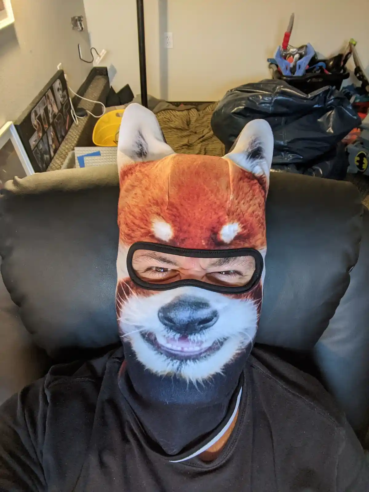 A person wearing a full-face red panda mask with the animal's facial features printed on it, including ears, eyes, nose, and…
