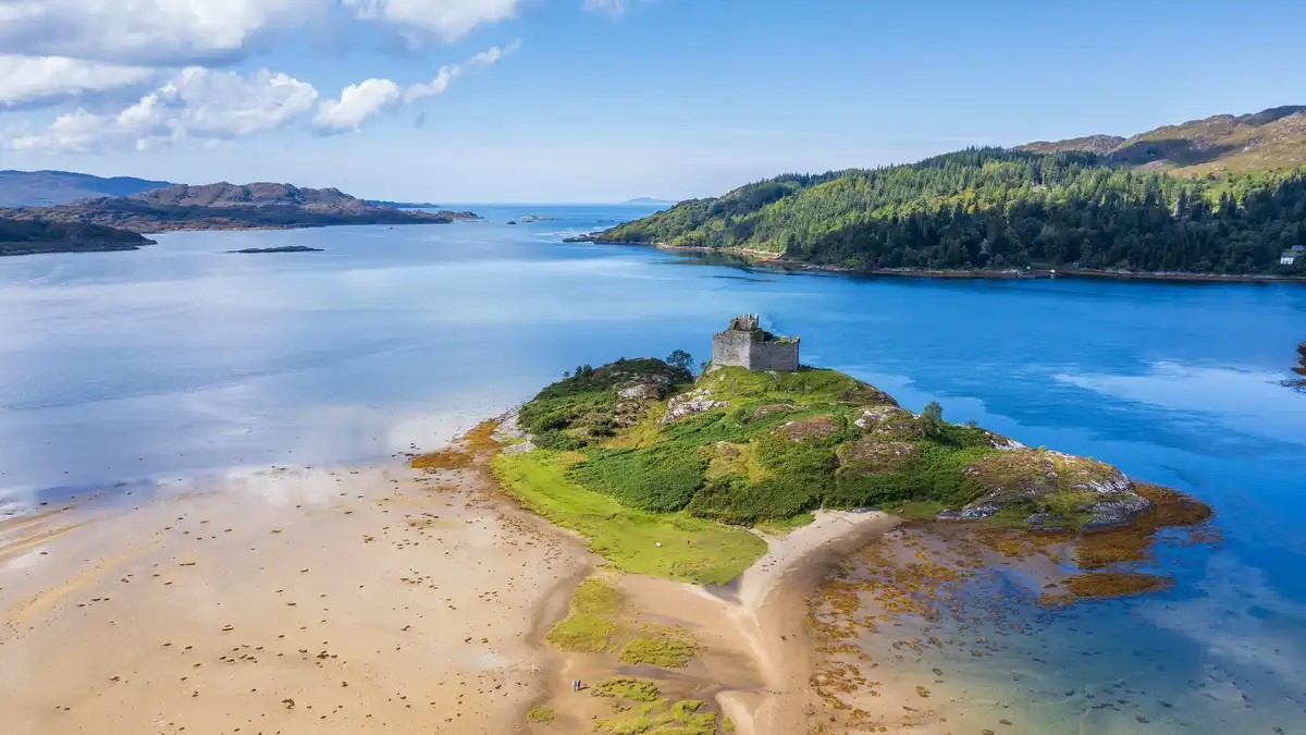 Tioram Castle, named "dry" in Scottish Gaelic, stands amidst a soggy setting. The surrounding Loch Moidart, a sea loch, is…