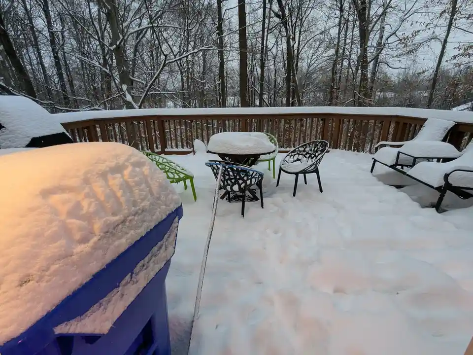 A snowy outdoor deck with furniture covered in snow, including a blue hot tub in the foreground. The text overlay reads 'i…
