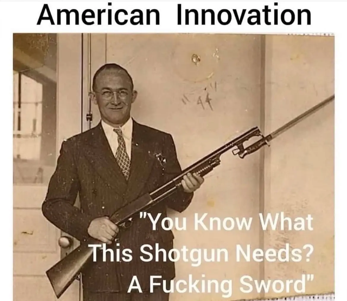 A sepia-toned historical photo shows a man in a suit and glasses holding a long shotgun with a sword-like bayonet attached…