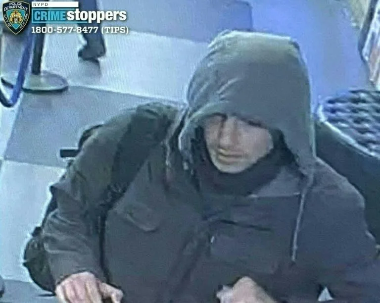 A grainy security camera image shows a person wearing a dark hooded jacket and scarf, looking downward with a neutral…