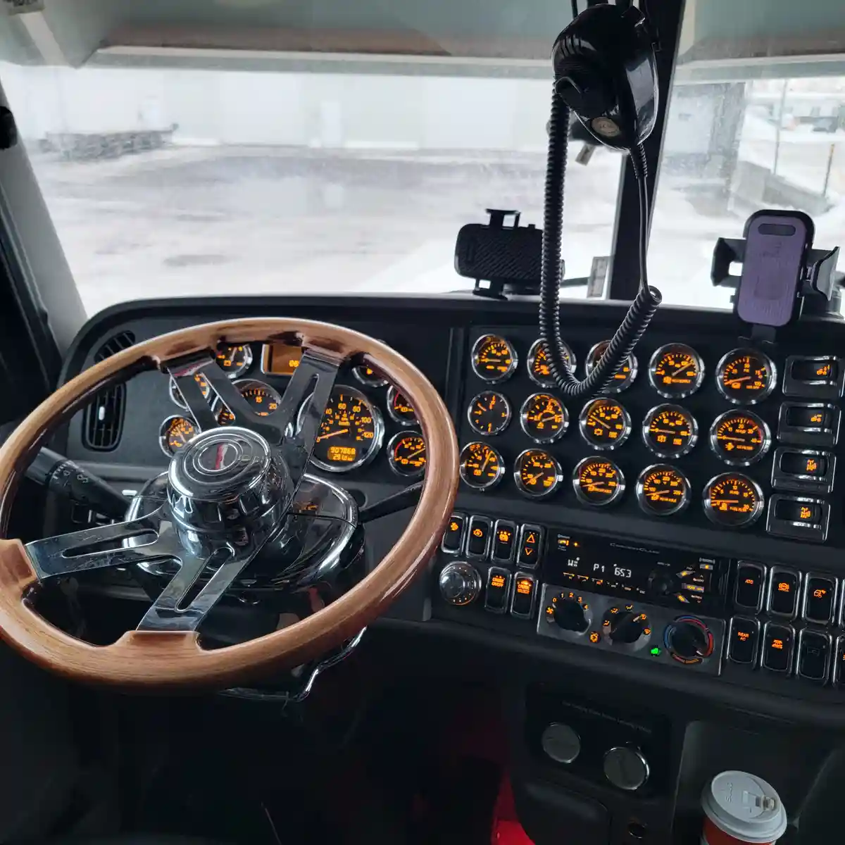 The image shows the interior of a truck cab with a wooden steering wheel, numerous illuminated gauges, and a dashboard with…