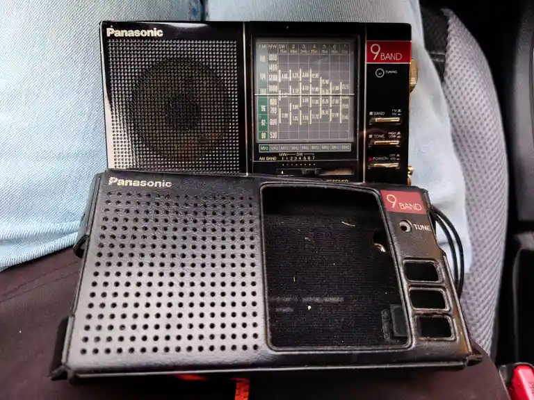 Two black Panasonic 9-band portable radios are shown, one with a functional display and the other with its speaker grille…