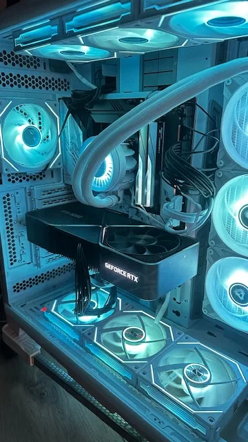 A high-end custom-built PC case with blue LED lighting illuminating multiple fans, a large graphics card labeled 'GEFORCE…