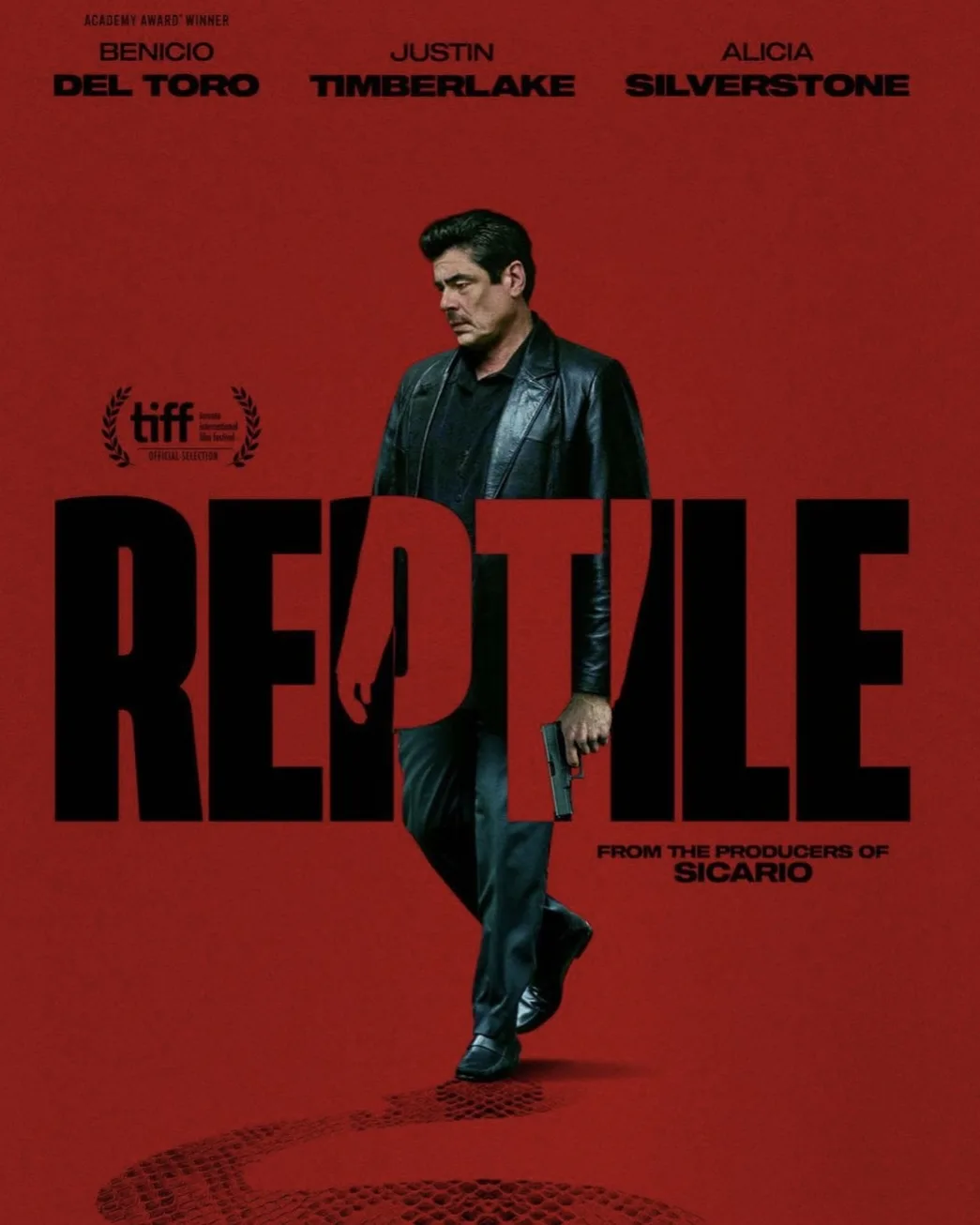 A movie poster for 'Reptile' featuring actor Benicio Del Toro in a black leather jacket walking forward while holding a…
