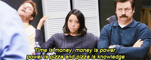 A still from the TV show 'Parks and Recreation' shows three characters in a meeting room. The man in the center, Ron…