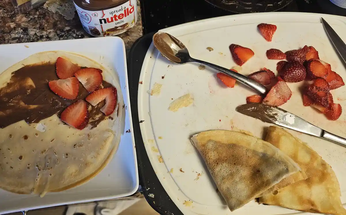 A split image shows a nearly full crepe with Nutella and strawberries on the left, and a mostly empty plate with leftover…